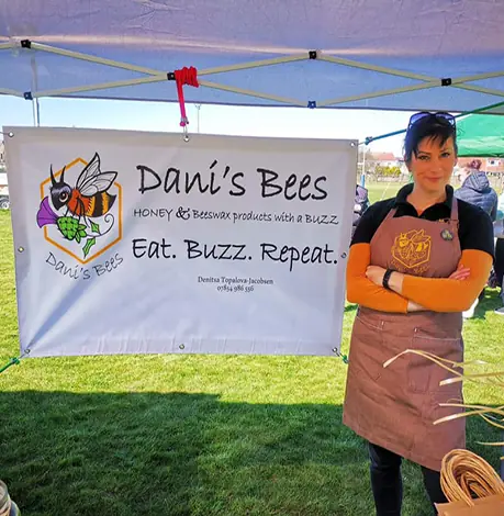 Dani from Dani's bees standing next to her stand with honey jars