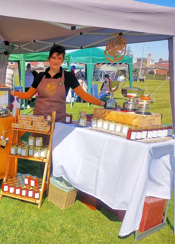 Dani next to her stand and jars of honey